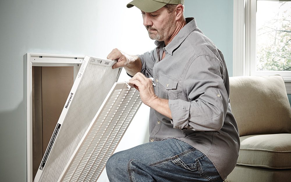 A man in grey shirt holding up a piece of metal.