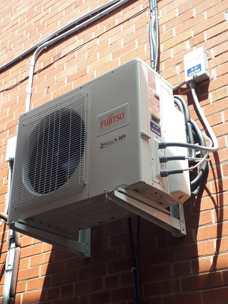 A wall mounted air conditioner unit on the side of a building.